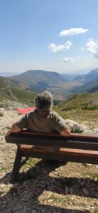 Flavio seduto su una panchina mentre guarda il panorama delle montagne